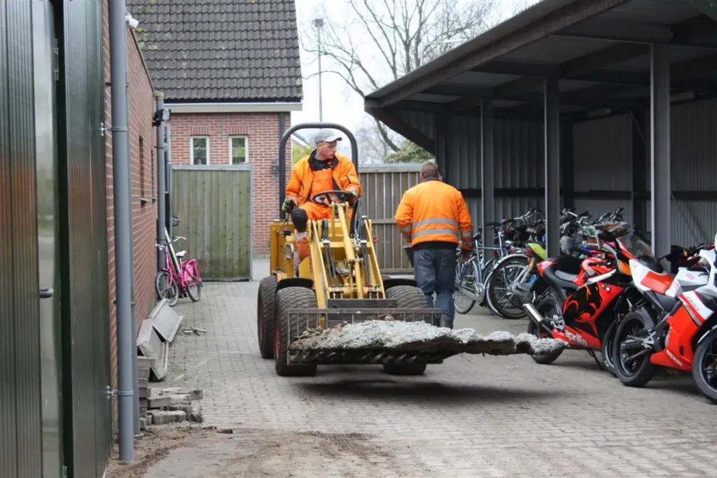 Shovel van Wierda Bestratingen voert puin af bij een bedrijfspand